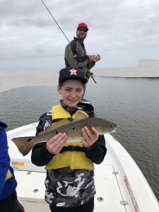 boy holding a medium size redfish on lake