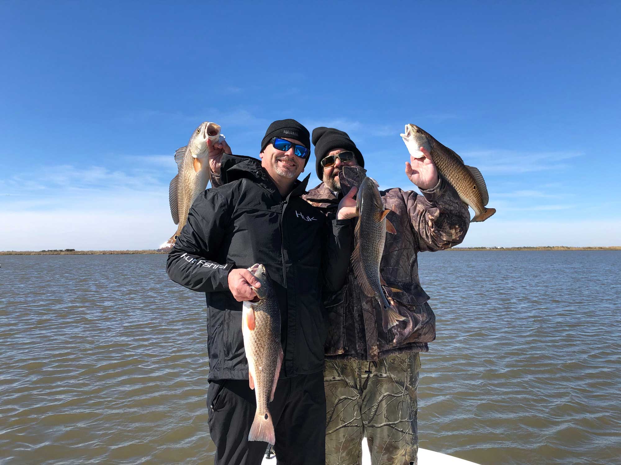 fishermen posing with large redfish on lake catherine