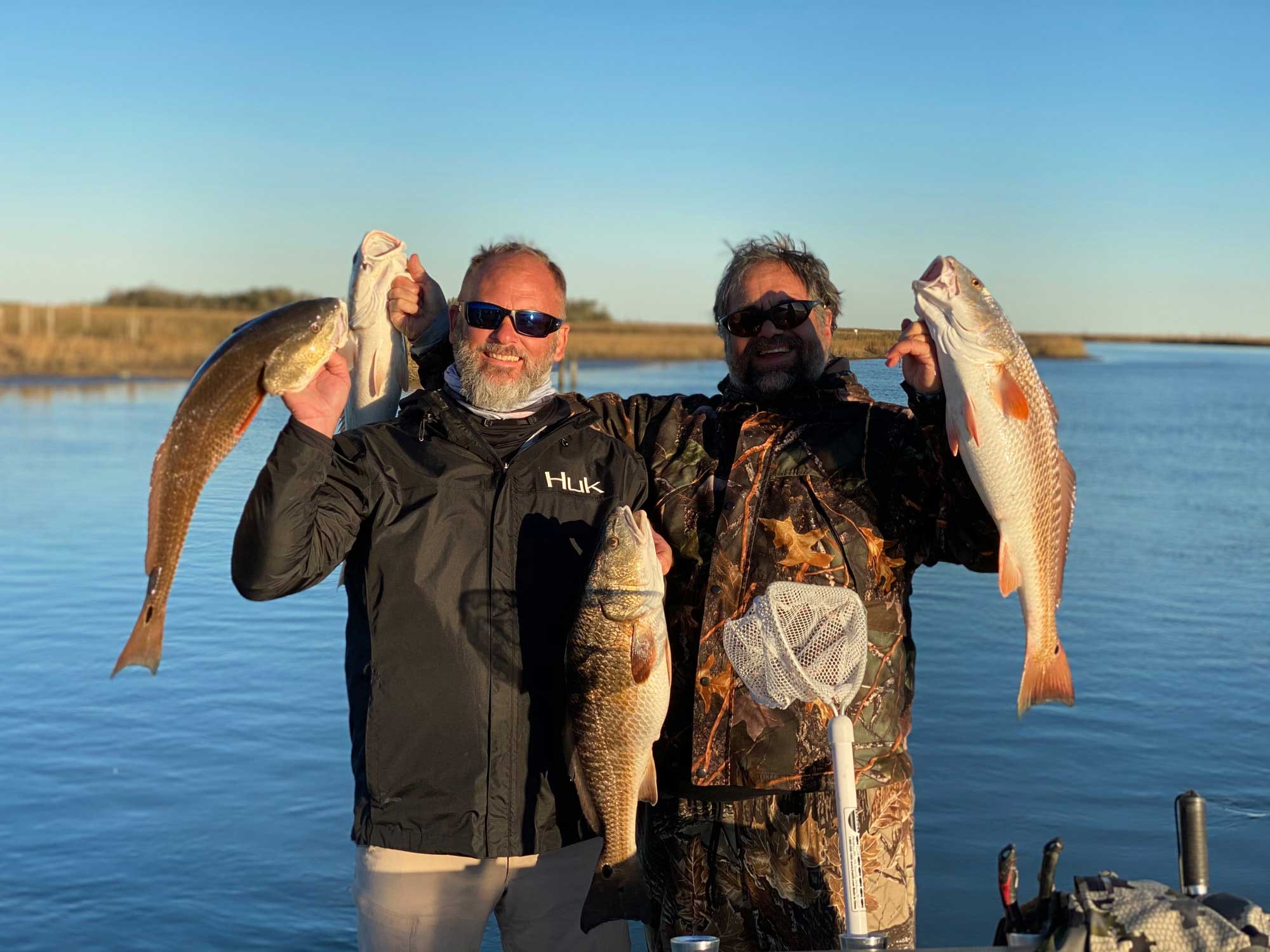 fishermen posing with large redfish on lake catherine